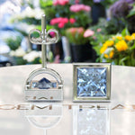 Load image into Gallery viewer, Celestial Charm: Princess-Cut Blue Moissanite Stud Earrings in Timeless Bezel Setting.