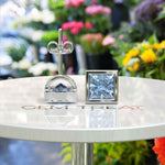 Load image into Gallery viewer, Celestial Charm: Princess-Cut Blue Moissanite Stud Earrings in Timeless Bezel Setting.