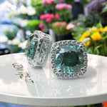 Load image into Gallery viewer, Ocean Radiance: Lustrous Cushion Cut Cyan Blue Moissanite Earrings in a Sparkling Halo.