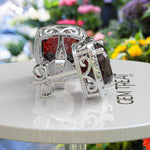 Load image into Gallery viewer, Crimson Allure: Cushion Cut Garnet Stud Earrings with Moissanite Halo.