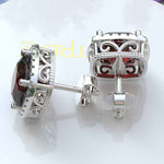 Load image into Gallery viewer, Crimson Allure: Cushion Cut Garnet Stud Earrings with Moissanite Halo.