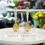 Load image into Gallery viewer, Golden Drops: Pear Cut Yellow Sapphire Drop Earrings with Moissanite Sparkle.
