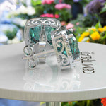 Load image into Gallery viewer, Ocean Radiance: Lustrous Cushion Cut Cyan Blue Moissanite Earrings in a Sparkling Halo.
