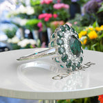 Load image into Gallery viewer, Emerald Oasis: Double Halo Oval Green Emerald Ring with Moissanite &amp; Emerald Embellishments.
