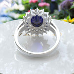 Load image into Gallery viewer, The Pinnacle of Romance: 4.0ct Oval Blue Sapphire Halo Ring Adorned with Moissanite Accents.
